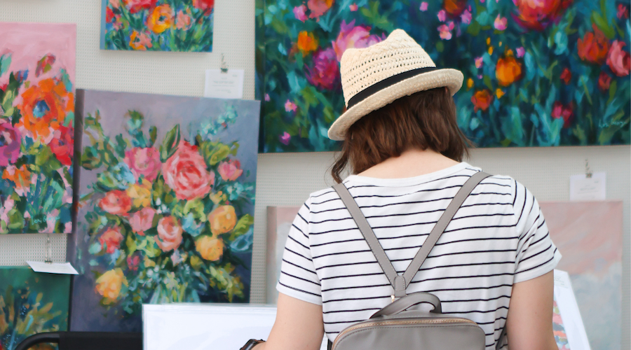 Woman examines paintings at Art Westport